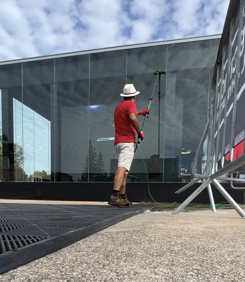Cleaning a glass facade from the ground, with a telescopic pole and purified water
