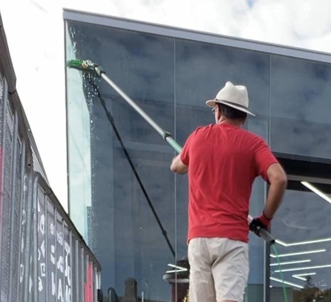 Purified water coming out of the brush on the telescopic pole and running down a glass facade